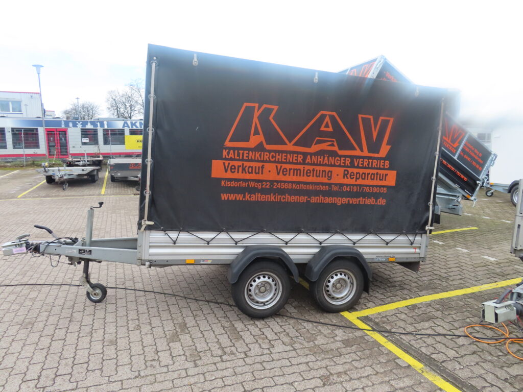 Seitenansicht eines schwarzen Planenanhängers mit orangenem KAV logo